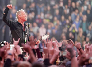 Lead singer and guitarist for Metallica , James Hetfield looking out at a sold out crowd pumping his fist in the air.