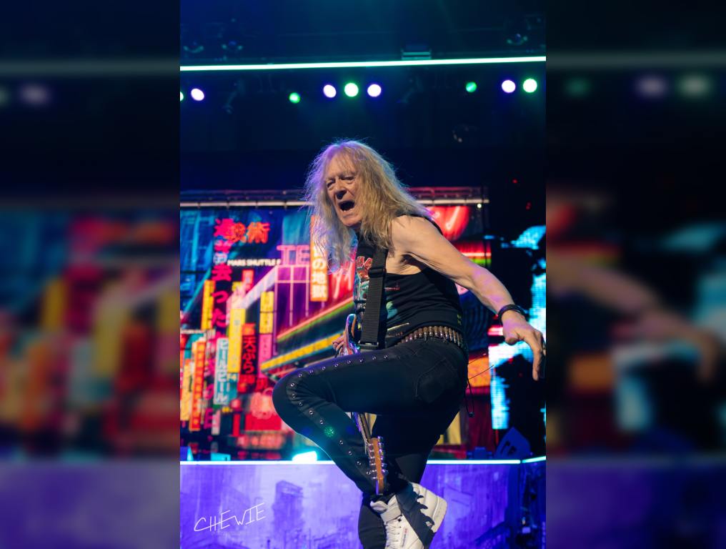 Iron Maiden's guitarist Janick Gers plays his guitar through his legs